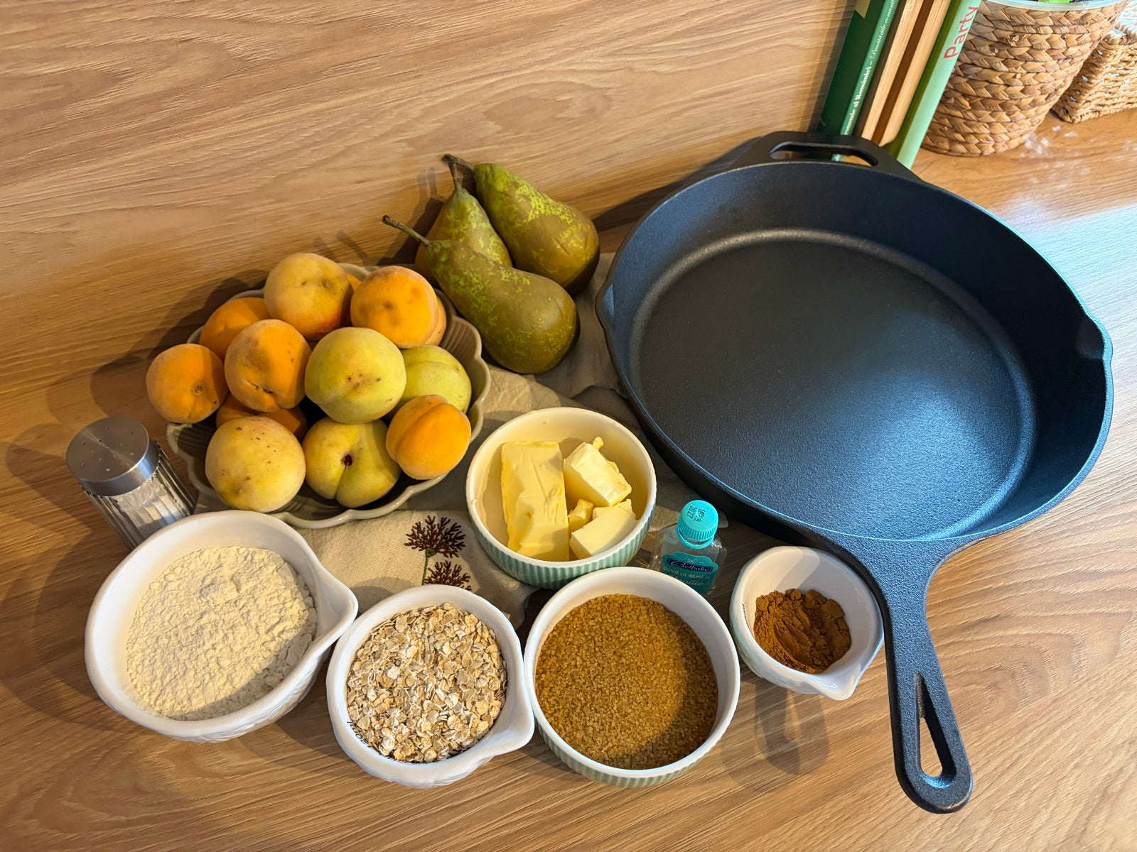 Ingrediente pentru crumble: pere, piersici, făină, fulgi de ovăz, zahăr brun, unt și scorțișoară, lângă tigaia de fontă