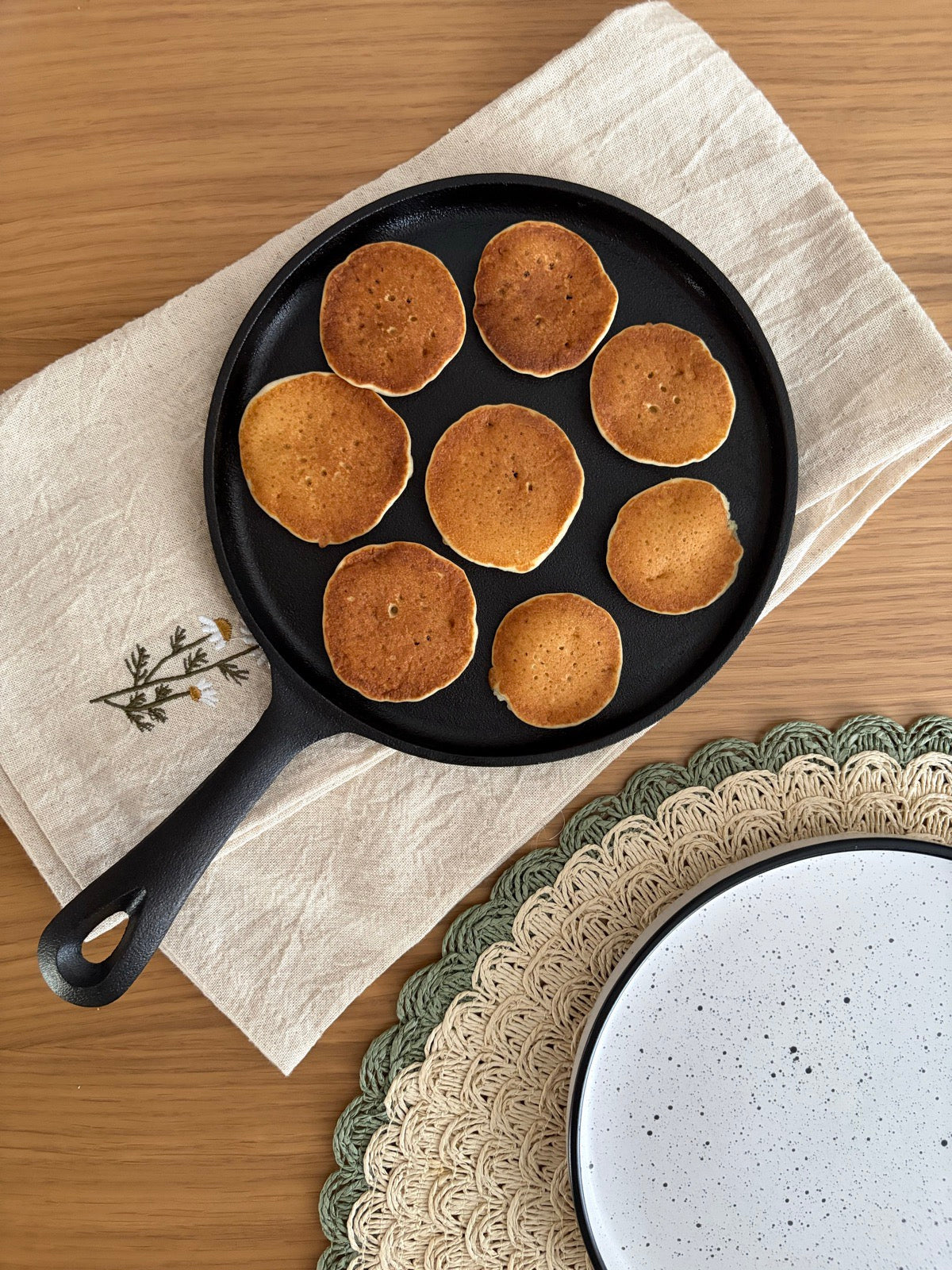 Opt mini pancakes rumenite uniform pe lespedea de fontă cu mâner, văzute de sus